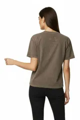 Remera de algodón, color gris oscuro con efecto gastado (acid wash), corte holgado y manga corta. Presenta un estampado frontal con motivos florales y texto en tonos rosados y blancos, incluyendo las frases "WILD ROSE ART", "ROSE POWER", "ST 1978" y "ROCKSTAR".