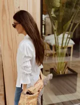 Camisa de algodón color marrón, con cuello clásico, cierre frontal de botones y mangas largas abullonadas con detalles de frunces elásticos y puños con volados.