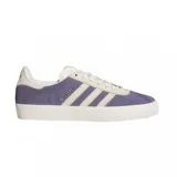 Championes Adidas Gazelle ADV de diseño clásico, confeccionados en gamuza color violeta con las icónicas tres tiras y detalles en color crema. Presentan suela de goma texturizada y el nombre del modelo grabado en dorado en el lateral.