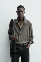 Sobrecamisa de corte cropped confeccionada en tejido ligero con algodón, con estampado de cuadros pequeños en tonos oscuros. Presenta cuello solapa, cierre frontal de botones, manga larga con puño abotonado y bajo con elástico en la espalda.