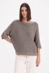 Sweater de tejido de punto con terminaciones de flecos en el cuello, mangas y ruedo. Presenta un corte holgado, mangas tres cuartos y una costura central vertical.