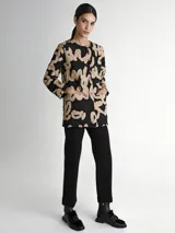 Saco acolchado con estampado abstracto en negro y beige, cuello redondo, cierre con botones a presión y bolsillos laterales. Incluye cinturón ancho de cuero negro con hebilla rectangular.