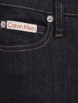 Pantalón de jean azul oscuro, de corte ajustado en la cadera y muslos, y acampanado a partir de la rodilla.