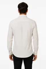 Camisa de poliéster color marrón, de corte holgado, con mangas largas, cuello camisero clásico y cierre frontal de botones.