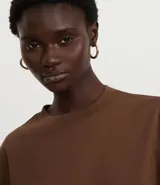 Remera cropped de manga corta, cuello redondo y calce oversized, confeccionada en tejido de algodón tipo media malla.