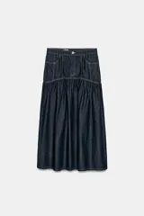 Falda midi de denim azul oscuro con tiro medio, bolsillos delanteros y costuras a contraste. Presenta un diseño con canesú estructurado y falda con frunces, cierre frontal con cremallera y botón metálico.