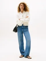 Cárdigan color crema de punto de algodón, con cuello redondo, cierre frontal con botones marrones, mangas globo, dos bolsillos delanteros y logo metálico en la manga.