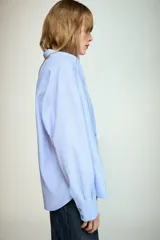 Camisa básica de corte clásico confeccionada en algodón, con cuello solapa, manga larga con puños abotonados, cierre frontal con botones y un bolsillo aplicado en el pecho.