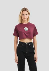 Remera cropped de algodón, color gris claro, con cuello redondo y manga corta doblada. Presenta un estampado frontal de un plátano amarillo.