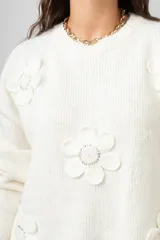 Buzo de punto color blanco, de corte holgado y cuello redondo, con diseño de flores aplicadas con detalles de mostacillas bordadas.