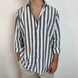 Camisa de lino a rayas verticales blancas y grises, de corte recto y mangas largas con puños abotonados.