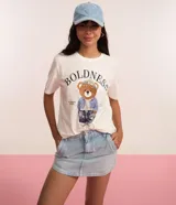 Remera de algodón color crudo, de corte recto y manga corta, con cuello redondo y estampa bordada de un oso vestido con chaqueta de jean, gorro y pantalón.