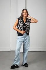 Chaleco tejido sin mangas con escote en V y cierre frontal de botones. Presenta un diseño estampado en contraste de color negro y gris, con un corte holgado y estilo oversize.
