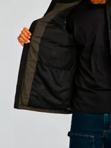 Chaleco puffer Caterpillar Arctic Zone Vest, modelo bicolor con parte superior negra y parte inferior en verde militar, cuello alto y cierre frontal con cremallera.