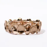 Pulsera elástica dorada con apliques circulares texturizados.
