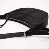 Bandolera negra con forma de medialuna, correa larga ajustable y cierre superior con cremallera.