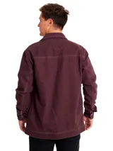 Chaqueta de gabardina color bordó, con cierre frontal de botones metálicos, bolsillos superiores con solapa y bolsillos laterales. Presenta costuras a la vista y etiqueta de la marca en el pecho.