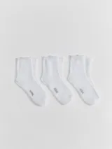 Kit de tres pares de medias unisex de caño medio, confeccionadas en tejido suave y elástico de color blanco, con el logo de la marca estampado en la planta del pie.