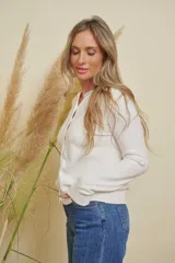 Saco blanco de punto con cuello redondo y detalles de strass en el escote. Tiene mangas largas y cierre frontal con botones.