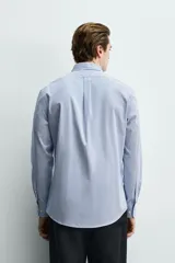 Camisa regular fit de algodón con diseño de rayas finas celestes y blancas. Cuenta con cuello abotonado, manga larga con puños abotonados y cierre frontal de botones.