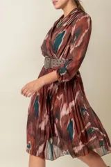 Vestido midi estampado con diseño abstracto en tonos marrones, verdes y blancos. Modelo cruzado con falda plisada y cintura elastizada.