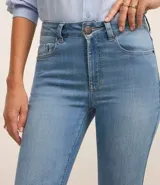 Pantalón flare de jeans con elastano, tiro alto, bolsillos delanteros y traseros, cierre con botón y cremallera, trabillas en la cintura.