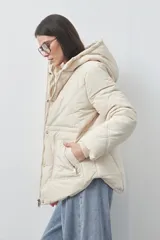 Campera puffer negra con diseño acolchado, capucha integrada y cierre frontal con botones a presión. Presenta puños elásticos y costuras decorativas en el frente.
