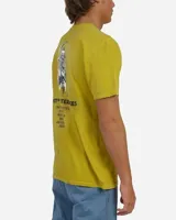 Remera de manga corta color verde mostaza, con efecto vintage dye y pequeño estampado gráfico en el pecho con la inscripción 'Lost Enterprises'.
