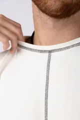 Musculosa oversize de algodón estilo sudadera, color crudo, con costuras visibles en contraste en color negro que recorren el centro verticalmente y enmarcan el cuello y el ruedo.