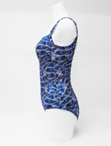 Malla entera estampada en tonos de azul, con escote en V, breteles regulables y un aplique metálico decorativo en el centro del busto. Cuenta con copa armada interna y forro.