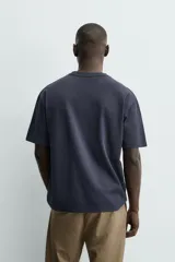 Camiseta de corte relajado confeccionada en algodón con textura irregular, cuello redondo y manga corta.