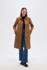 Abrigo tipo gabardina o trinchera de largo medio, color camel, con cuello camisero y cierre frontal de botones dorados. Presenta un corte recto y holgado.