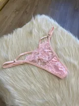 Tanga de encaje floral color rosa, con tiras finas regulables.