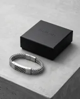 Pulsera de acero inoxidable con placa central rectangular que presenta un diseño de patrón de tablero de ajedrez grabado y cadena de eslabones tipo bizantina.