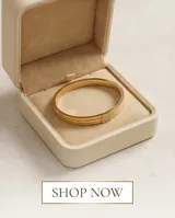 Pulsera tipo esclava rígida de acero con baño de oro, compuesta por tres bandas paralelas y un detalle central cuadrado adornado con circonias.