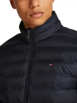 Campera puffer Tommy Hilfiger color azul marino, con cuello alto, cierre frontal con cremallera, bolsillos laterales con cremallera y logo bordado en el pecho.
