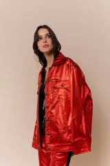 Chaqueta de cuerina metalizada negra con corte oversized y logo bordado en las mangas. Tiene cuatro bolsillos, dos de ellos internos.