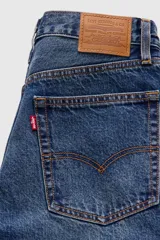Jeans de denim azul de corte amplio y bota ancha, tiro medio, con efecto ligeramente lavado en las piernas y diseño clásico de cinco bolsillos.