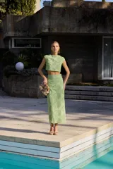 Top corto de color verde lima con diseño calado de motivos circulares y abanicos. Presenta cuello a la caja, sin mangas y un corte recto tipo crop top.