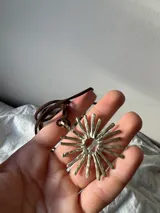 Colgante con dije en forma de sol con rayos, hecho a mano en alpaca, con cordón de gamuza marrón.