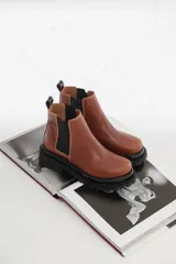 Botas tipo chelsea de cuero con suela track dentada y paneles elásticos laterales. Presentan costuras a contratono y tirador en la parte trasera.