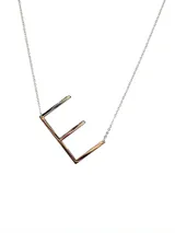 Collar plateado con dije de la letra G mayúscula.