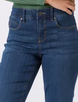 Jean de tiro alto con corte bootcut, ajustado en cadera y muslos con una sutil apertura desde la rodilla. Presenta diseño clásico de cinco bolsillos, cierre con botón y costuras en contraste. Su diseño posterior incluye costuras estratégicas para un efecto de realce en la silueta.