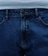 Pantalón de jean slim color azul, con lavado medio y acabado uniforme. Cuenta con cintura con presillas, cierre frontal con botón y cremallera, y bolsillos funcionales en la parte delantera y trasera.