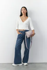 Cartera bandolera color lila de cuero sintético texturizado, con dos compartimentos con cierre imantado y un bolsillo externo con solapa y tachas. Incluye correa desmontable y regulable.