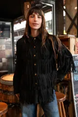 Chaqueta de gamuza marrón con diseño de flecos en la parte delantera y las mangas, corte tipo camisa y cierre frontal de botones.