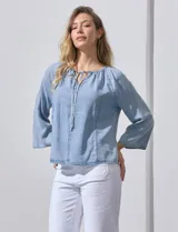 Blusa celeste de lyocell con cuello a la base y escote en V con lazo de ajuste. Manga larga amplia.
