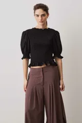 Pantalón marrón de corte ancho y fluido, con pinzas frontales y tiro alto.