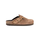 Zueco de estilo casual confeccionado en gamuza color marrón, con diseño de punta cerrada y ajuste mediante una correa con hebilla metálica lateral. Cuenta con una suela de corcho y base de goma antideslizante.