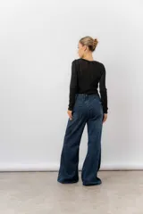 Jean de tiro alto con corte wide leg y pierna amplia. Confeccionado en denim rígido de lavado azul clásico, cuenta con bolsillos funcionales y cierre frontal.